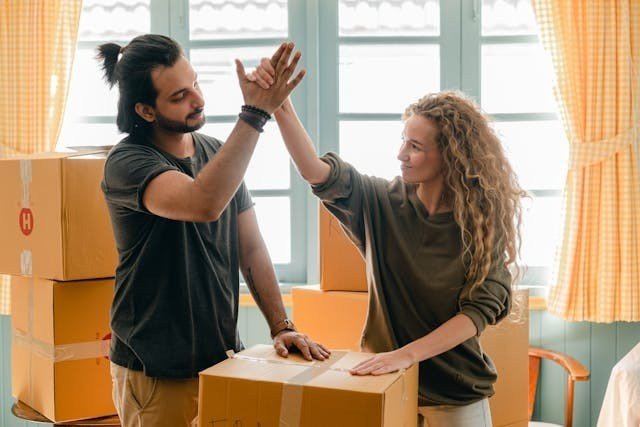 A couple giving each other a high five while packing for a move