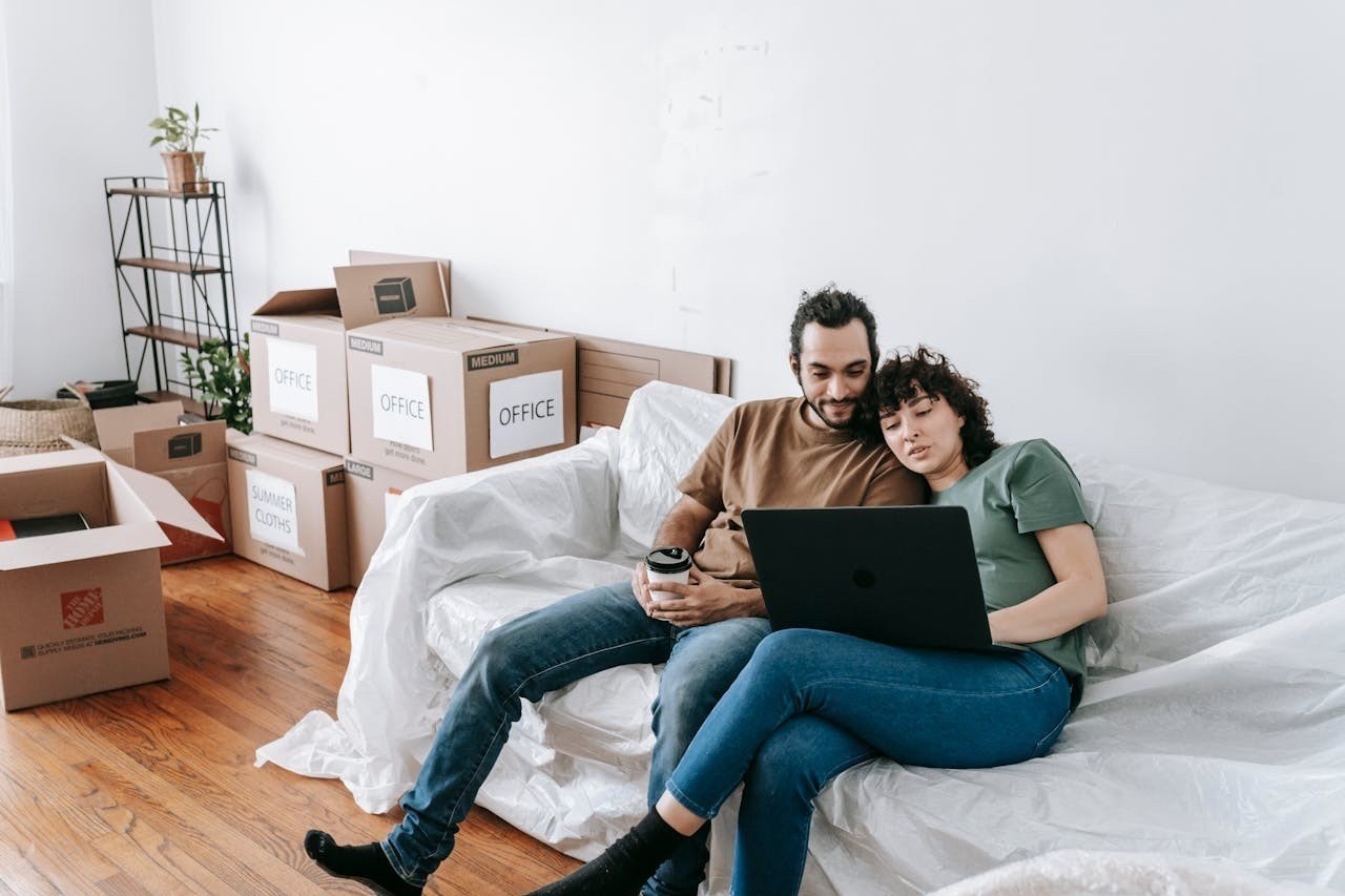 A couple sitting on a couch and watching on a laptop.